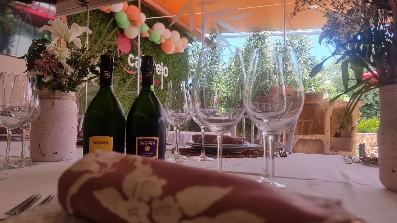 Mesa preparada para una celebración en la terraza de Cañarejo, con champán y flores